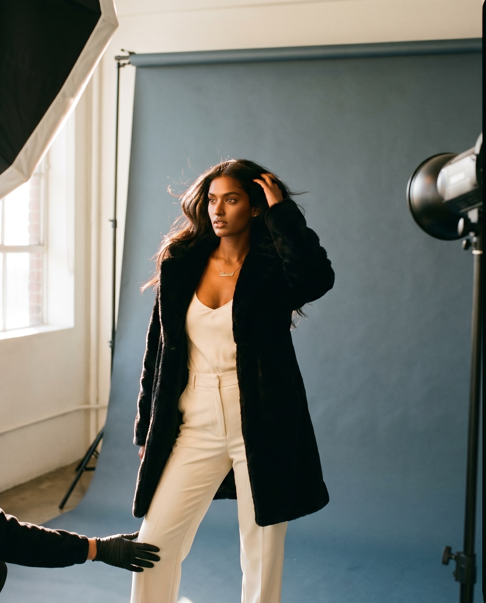 A creator on a seamless backdrop in a photo studio, dramatic editorial coat, controlled lighting.