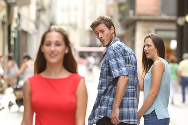 Distracted boyfriend meme — man looking back at another woman while his girlfriend looks at him